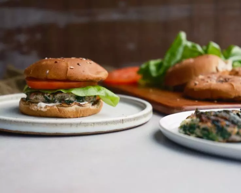 A vegan burger with spinach, lettuce, and a tomato on a plate.