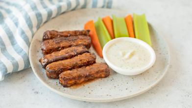 Buffalo Tempeh Wings on plate with celery and carrots and dipping sauce