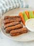 Buffalo Tempeh Wings on plate with celery and carrots and dipping sauce