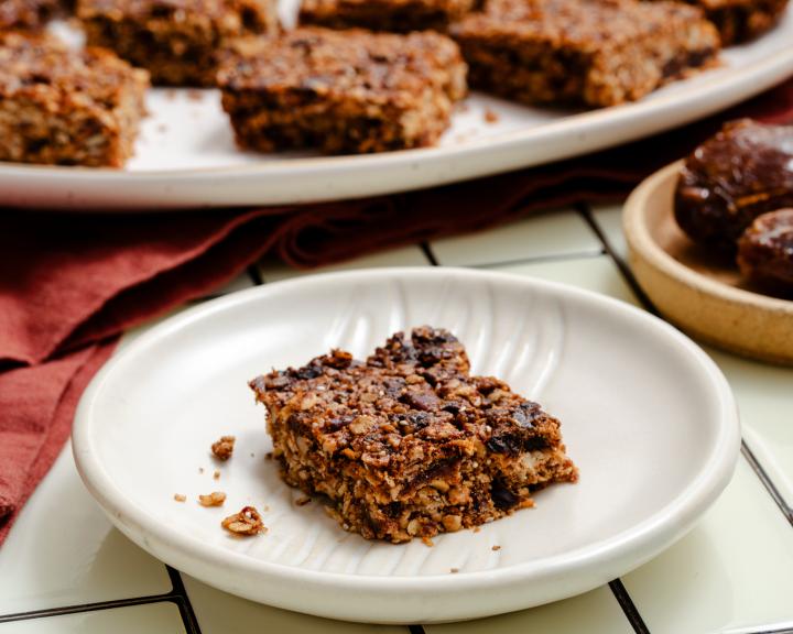 A plate with a slice of California date breakfast bar with more bars in the background for healthy sweet snack