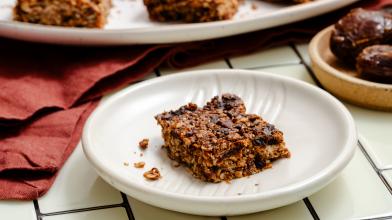 A plate with a slice of California date breakfast bar with more bars in the background for healthy sweet snack