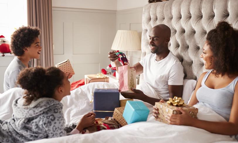 Family Opening Presents In Bed On Christmas Morning