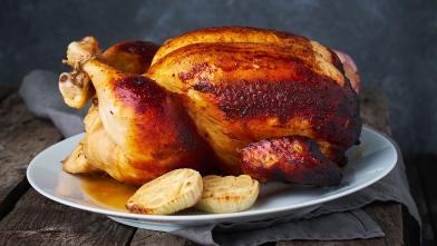 Whole roasted chicken on a plate with onions