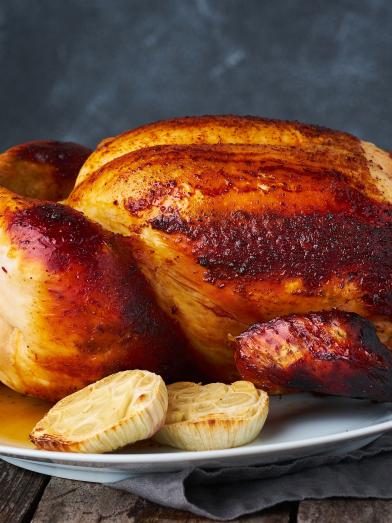 Whole roasted chicken on a plate with onions