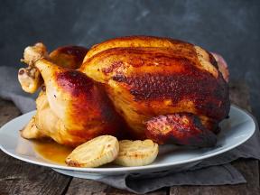 Whole roasted chicken on a plate with onions