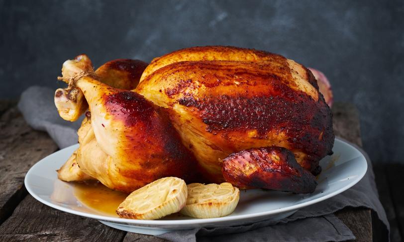 Whole roasted chicken on a plate with onions