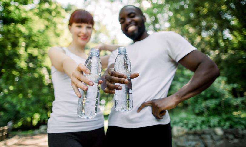 Smiling couple out for a jog in park holding water bottles