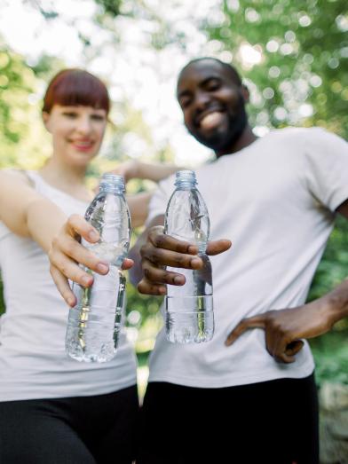 Smiling couple out for a jog in park holding water bottles