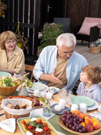 Multi-generational family eating healthy meal at picnic table