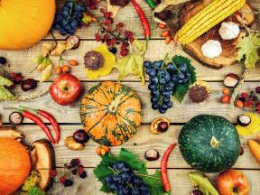 Various fall fruits and vegetables on a wooden surface.
