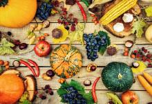 Various fall fruits and vegetables on a wooden surface.