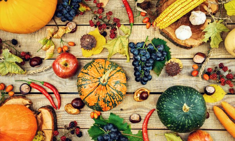 Various fall fruits and vegetables on a wooden surface.