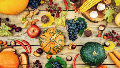 Various fall fruits and vegetables on a wooden surface.