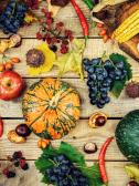 Various fall fruits and vegetables on a wooden surface.