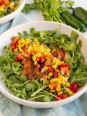 A bowl of grilled tilapia on a salad of arugula and corn for a heart and diabetes healthy dash diet