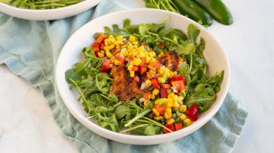 A bowl of grilled tilapia on a salad of arugula and corn for a heart and diabetes healthy dash diet