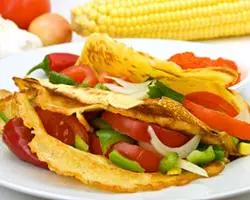 Savory crepe with vegetables and corn in the background