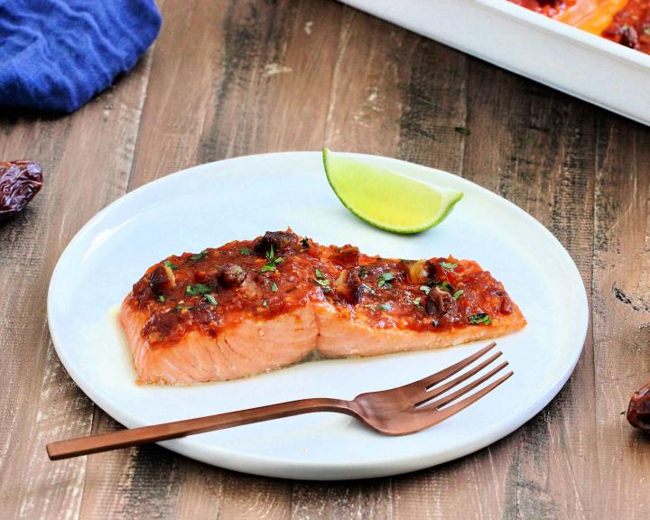 Salmon filet on white plate with harissa sauce and California dates