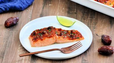Salmon filet on white plate with harissa sauce and California dates