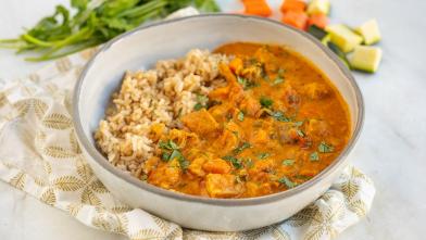 A bowl of richly spiced Indian butter chicken served with brown rice for a health Indian diet