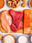An assortment of protien rich foods like chicken, steak, salmon, almonds, eggs, and nuts. 