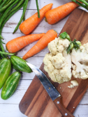 A chopping board with cauliflower surrounded by veggies perfect for a healthy diabetic diet